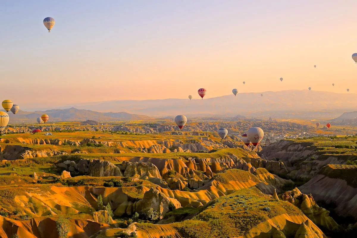 Hőlégballonok napfelkeltében egy különleges táj felett